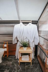 two white shirts hanging on a rack in a bathroom at תניא in Gilon