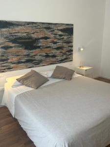 1 cama con 2 almohadas y una pintura en la pared en Civico 28 en Pescara