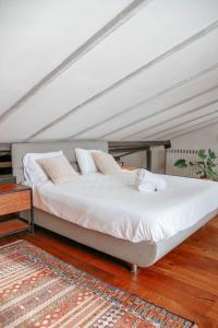 1 cama con sábanas blancas y almohadas en una habitación en תניא, en Gilon
