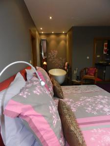 a bedroom with a bed with pink and gray sheets at O Sixième Sens in Williers