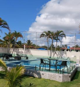 - une table et des chaises à côté de la piscine dans l'établissement Villa Saudade, à Porto Seguro