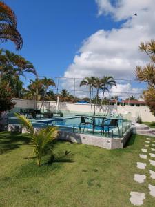 una piscina con mesas de picnic y palmeras en Villa Saudade, en Porto Seguro