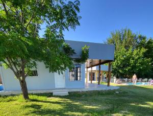 uma pequena casa branca com uma árvore num parque em Posada y Cabañas "Finca El Rincón de Lunlunta" em Mendoza