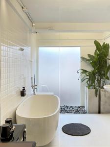 uma casa de banho branca com uma banheira e uma planta em Chatel BKK em Bang Rak