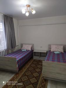 um quarto com 2 camas e uma janela em SunRay Guest House-Hostel em Karakol