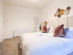 a bedroom with a large white bed and a clock on the wall at Attractive 3 Bedroom Apartment in Polmadie