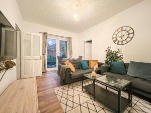 a living room with a couch and a clock on the wall at Attractive 3 Bedroom Apartment in Polmadie