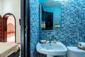 W wyłożonej niebieskimi kafelkami łazience znajduje się umywalka i toaleta. w obiekcie Riad Haj Thami w Marakeszu