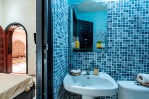 a blue tiled bathroom with a sink and a toilet at Riad Haj Thami in Marrakesh