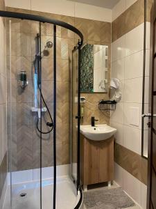 La salle de bains est pourvue d'une douche et d'un lavabo. dans l'établissement Inna Strefa - Sleep & Restaurant, à Inowrocław