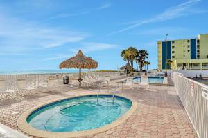 a swimming pool with an umbrella and the ocean at Sea Breeze 705 in St Pete Beach