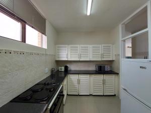 a kitchen with a stove and a white refrigerator at Umhlanga Beach 3 Bedroom Apartment in Durban