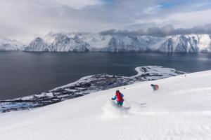 two people are skiing down a snow covered slope at Lyngenfjord,Odins Hus in Olderdalen
