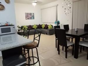 een woonkamer met een bank en een tafel en stoelen bij BEACH HAUS-Suites Vacacionales in Playa del Carmen