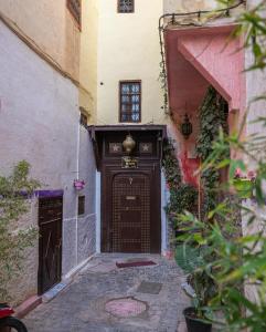 an alley with a large wooden door in a building at Riad bel kaid fes in Fès