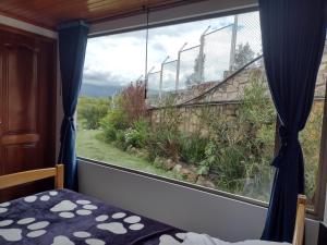 1 dormitorio con ventana grande con vistas en Lujosa Casa Quinta en Naturaleza Andina, en Iza
