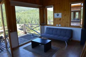 a living room with a blue couch and a table at BH-Meliquina, Colgantes al Río in Villa Meliquina