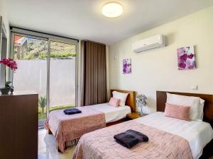 a hotel room with two beds and a window at Casa Inês by LovelyStay in Arco da Calheta +26 photos