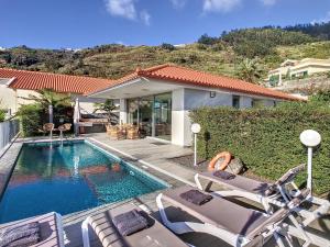 a swimming pool with chairs and a house at Casa Inês by LovelyStay in Arco da Calheta