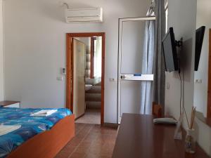 een slaapkamer met een bed, een tafel en een televisie bij Albergo Bel Tramonto in Porto Azzurro