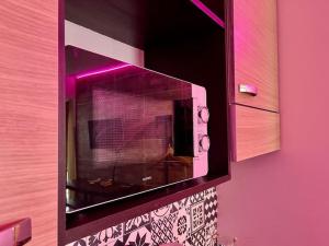 a microwave oven with purple lights on a wall at Parking + piscine, tout confort, proche aéroport & mer in Saint-Laurent-du-Var