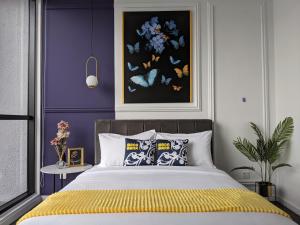 1 dormitorio con paredes moradas y 1 cama con manta amarilla en Scarletz Suites KLCC by Mana-Mana, en Kuala Lumpur
