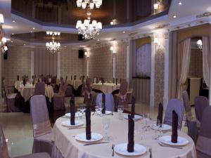 a banquet room with tables and chairs and chandeliers at 1001 Noch Hotel in Tolyatti