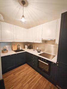 a kitchen with black cabinets and white counter tops at M&K Apartament Szafirowy - Wyspa Sobieszewska in Gdańsk