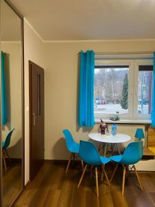 a dining room with a table and blue chairs at Apartamenty i Pokoje Gościnne ALA II in Szklarska Poręba