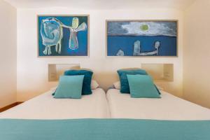 a bedroom with two beds and paintings on the wall at Eco Suites Caves in La Laguna