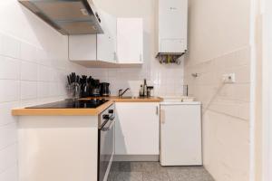 a kitchen with white cabinets and a refrigerator at Designer Apartments, 2 min to U1 Reumannplatz in Vienna