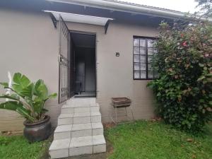 uma casa branca com uma porta preta e uma planta em Aloe Cottage - Ramsgate Ramble Rest em Margate