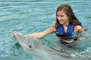 a girl in the water with a dolphin at Peninsula Esmeralda Luxury Villas in San Felipe de Puerto Plata