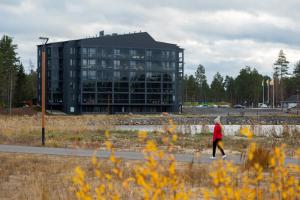 a woman walking down a road in front of a building at Asunto Kalajoen Golfpuistossa in Kalajoki