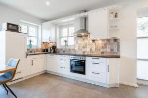 a kitchen with white cabinets and a stove top oven at Ferienhaus Maira, mit Garten und Sauna in Greetsiel