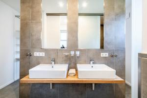 two sinks in a bathroom with two mirrors at Ferienhaus Maira, mit Garten und Sauna in Greetsiel