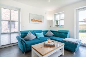 a living room with a blue couch and a table at Ferienhaus Maira, mit Garten und Sauna in Greetsiel