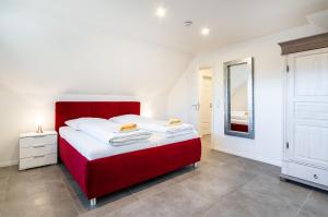 a bedroom with a red bed and a mirror at Ferienhaus Maira, mit Garten und Sauna in Greetsiel