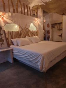 a bedroom with a large bed with white sheets at Paraiso de Arcilla - Suite & Glamping in Ráquira