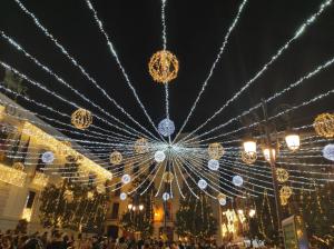 un grupo de personas de pie en frente de un edificio con luces de Navidad en Apartamento Castillo, en Granada