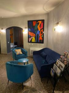 a living room with blue couches and a painting at La Roselière in Saint-Quentin-Fallavier