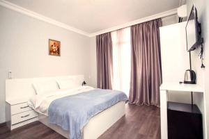 a white bedroom with a bed and a window at Astoria Sky in Tbilisi City