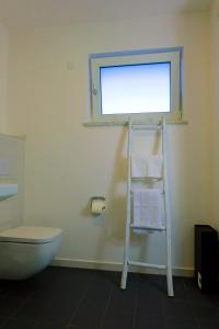 a bathroom with a toilet and a shelf with towels at Design Apartment Nr 1 mit Terrasse und Parkplatz in Straubing
