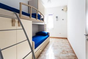 une chambre avec lits superposés avec des lits bleus et une échelle dans l'établissement Appartamento climatizzato a 50 m dal mare nel centro di Torre San Giovanni, à Torre San Giovanni