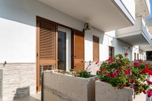un bâtiment avec des fleurs devant une porte dans l'établissement Appartamento climatizzato a 50 m dal mare nel centro di Torre San Giovanni, à Torre San Giovanni