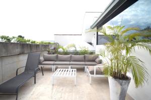 um pátio com um sofá e cadeiras numa varanda em AmazINN Places Rooftop and Jacuzzi I na Cidade do Panamá