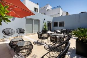 een patio met stoelen en tafels en een parasol bij Hotel Bys Palermo in Buenos Aires