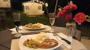 a table with two plates of food and two glasses of wine at Glamping Paraíso Escondido in Anapoima