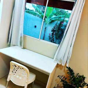 ventana con escritorio blanco y silla en una habitación en Mar e Sol Chalés SMG, en São Miguel do Gostoso