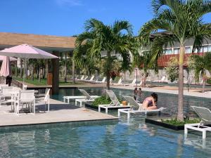 uma mulher sentada numa piscina num resort em Ilê de Pipa Blz em Pipa